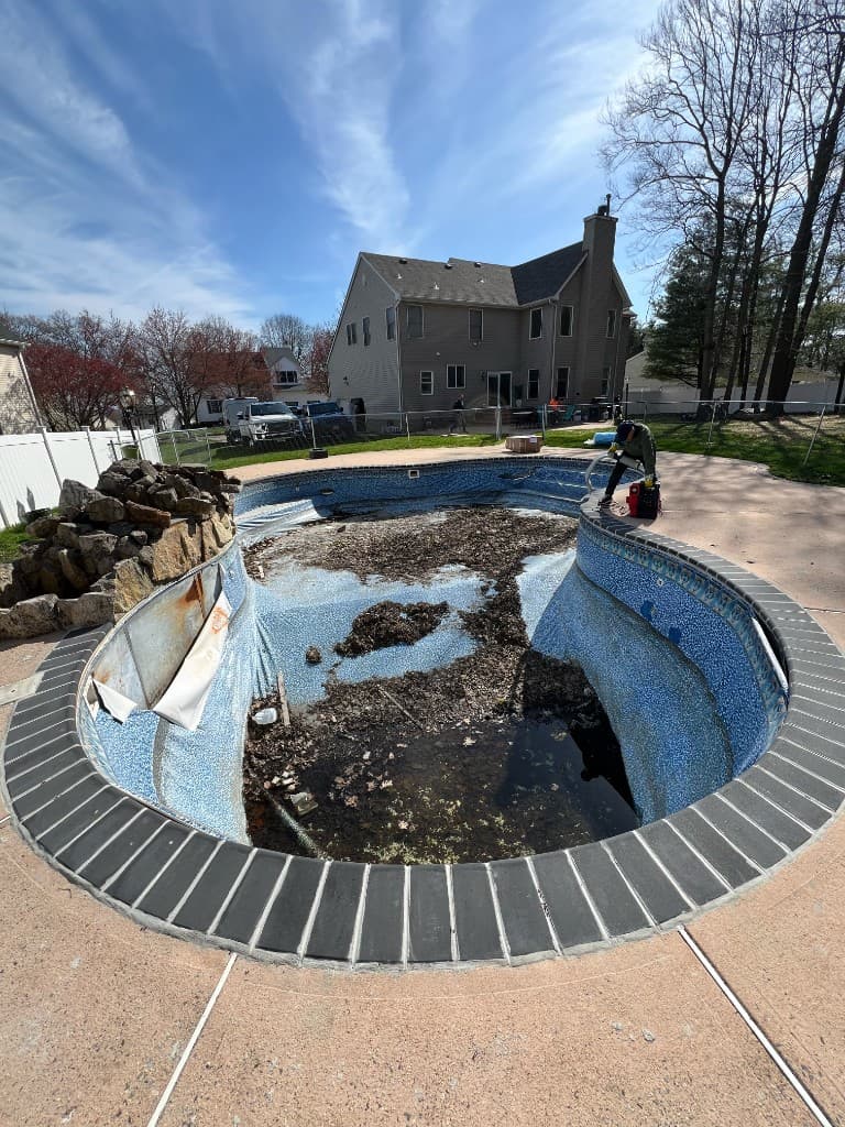 Before: drained pool, debris cleared, liner failing at the walls, crew staged vacuums on the coping.