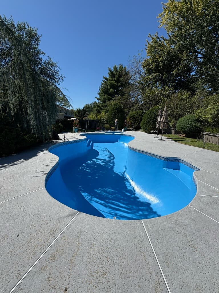 Kidney pool shell with bright interior finish and light concrete deck, ready for fill, equipment start-up, and final leak retest after structural or resurfacing work.